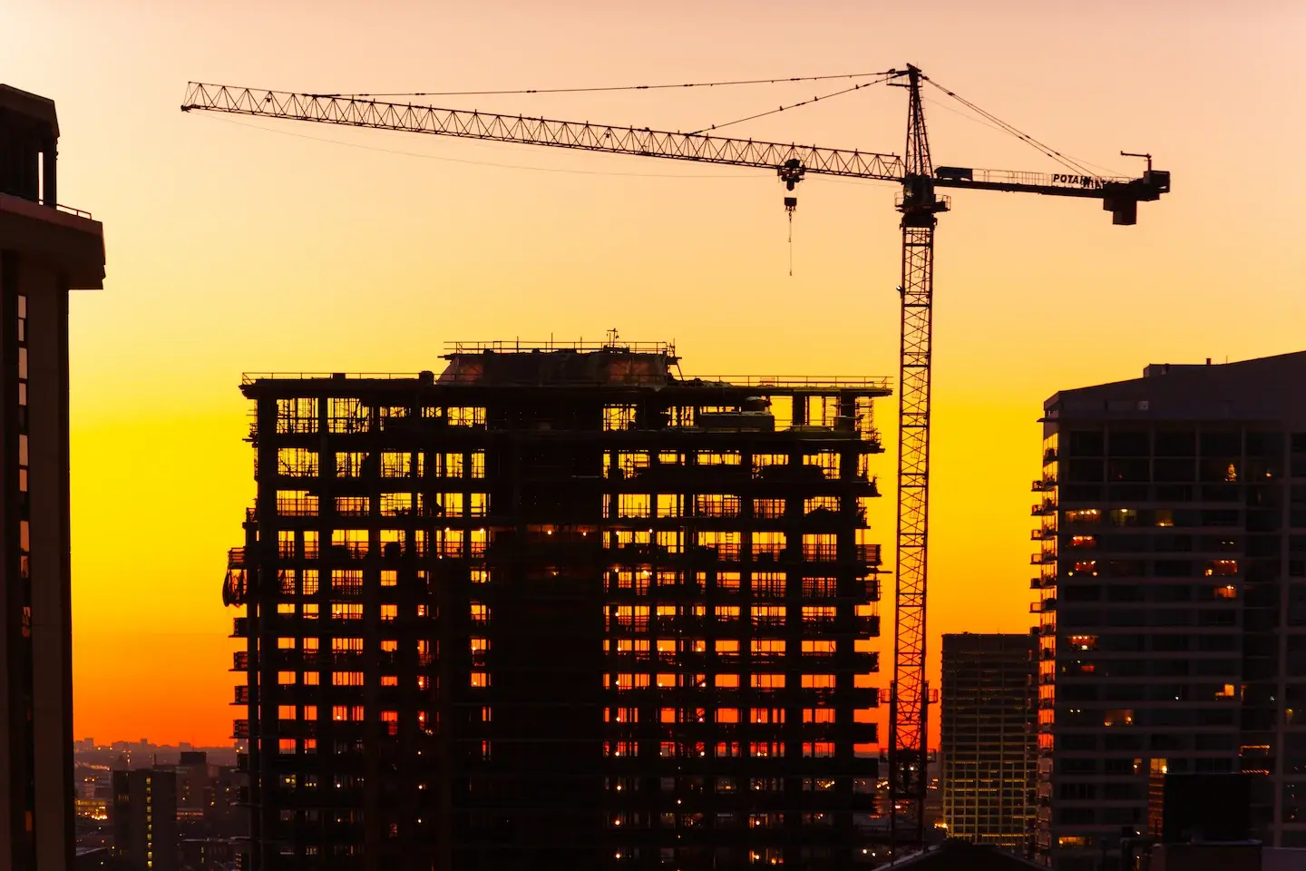 Cranes and a building under construction at sunset